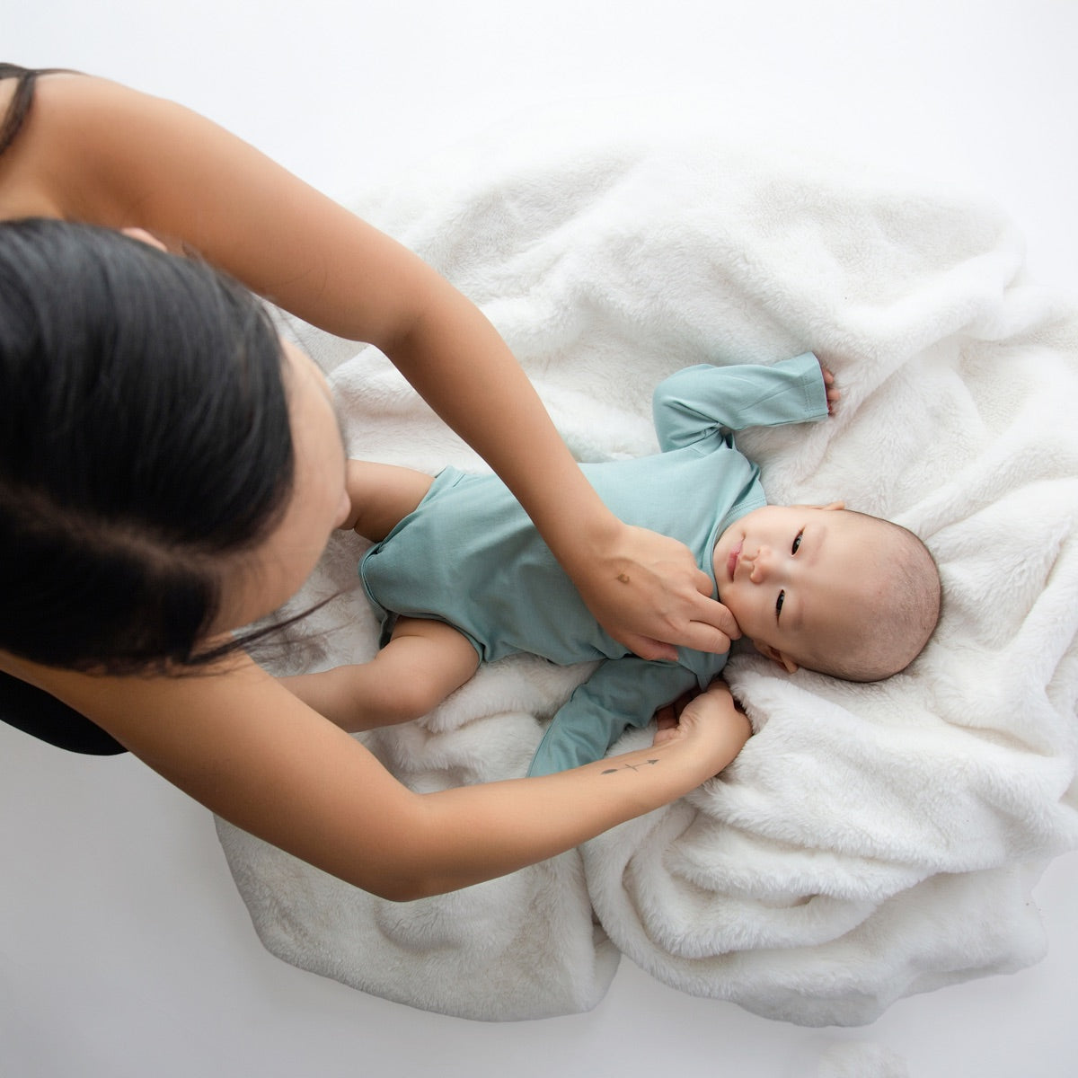 Parent dressing a baby in a Bloom Singlet with shoulder snaps